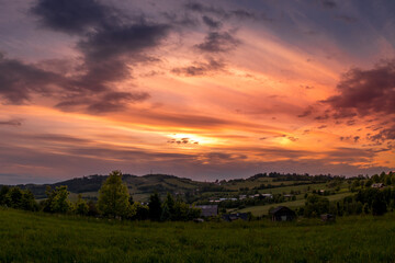 Landscape full of hills and mountains with clouds and blue sky with sun during colorful sunset Beskydy region.