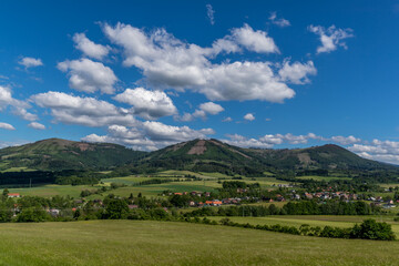 Ondrejnik and views of other Beskydy hills and mountains with white clouds and blue sky in the background during a sunny day.