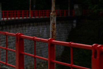 Fototapeta na wymiar Red railings and stony dam of the Bystricka reservoir after a rainy afternoon.