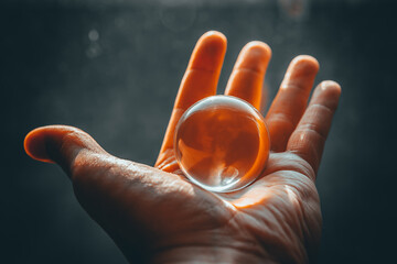 Men's hand holding a small glass purchase in the palm of his hand during sunset.