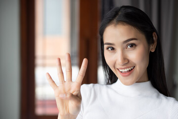 asian woman pointing, counting four finger, portrait of happy smiling asian woman pointing up 4 fingers for number four or 4 points concept by Chinese asian adult woman model, casual theme indoor