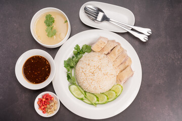 Hainanese chicken rice. Roasted Chicken Rice with soup, vegetable and Garlic, chili, ginger sauce on gray background.