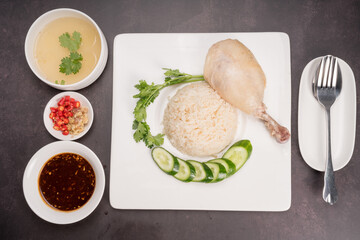 Hainanese chicken rice. Roasted Chicken Rice with soup, vegetable and Garlic, chili, ginger sauce on gray background.