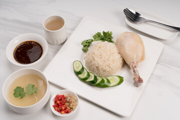 Hainanese chicken rice. Roasted Chicken Rice with soup, vegetable and Garlic, chili, ginger sauce on marble background.