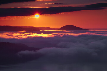 朝陽に照らされて赤く染まる空と雲。ドラマチックな夜明けの風景。日本の北海道、美幌峠で。