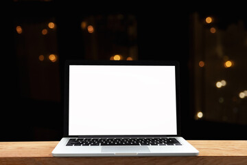 Notebook or laptop with blank screen on wooden table on blurred background in modern cafe restaurant bokeh light and light bulbs