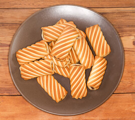Tubular cookies with jam filling on brown dish, top view