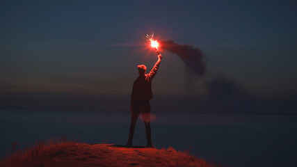 The man holding a fire stick on the mountain top near the sea