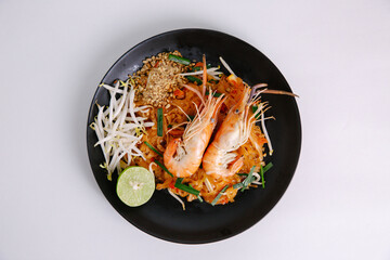 Udon noodle pad thai with shrimp in black plate white background top view asian food Copy space