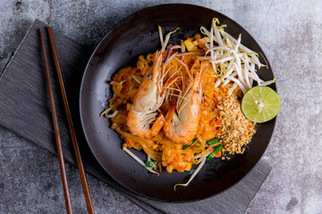 Udon Pad Thai with shrimp in a dark background, top view Asian style food Copy space