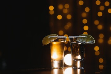Tasty alcohol drink cocktail tequila with lime and salt on vibrant dark background. Closeup.