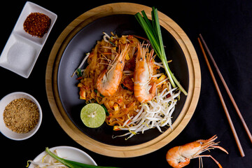Udon Pad Thai with shrimp in a dark background, top view Asian style food Copy space