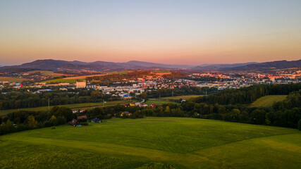 Fototapeta na wymiar Aerial landscape view at orange sunset with field and village lying in the background.