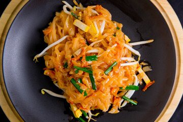 Udon noodles, pad thai, vegetarian vegetables on black plate, top view Asian Vegetarian Copy space