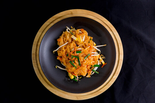 Udon noodles, pad thai, vegetarian vegetables on black plate, top view Asian Vegetarian Copy space