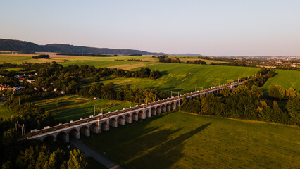 Aerial view of the railway viaduct near Lipnik nad Becvou with the surrounding countryside and the village lying nearby during the late afternoon.
