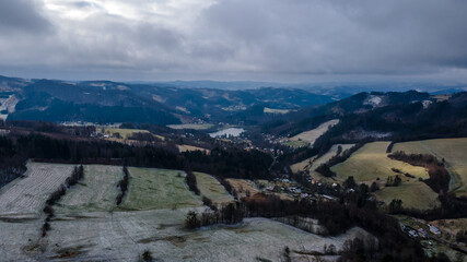 Aerial view of a hilly landscape with freshly fallen snow during a light snowfall in the Beskydy region.