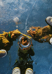 family is photographing on a mobile phone on a frozen lake, dad and kids make selfie in the reflection of ice, people shooting a hole for fishing on icebound river