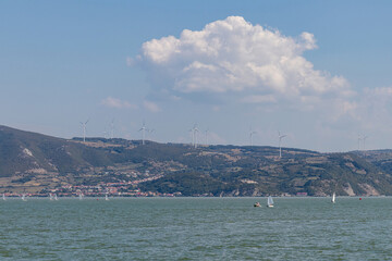 Hilly bank over the river with wind turbine towers