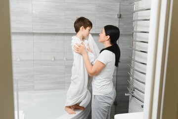 Mother washing little son in bathroom