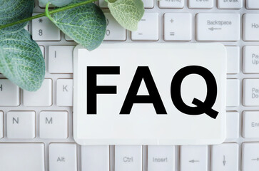 FAQ Text (Frequently Asked Questions) text on white paper on white keyboard