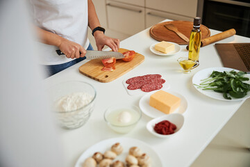 Slicing tomato while getting all the ingredients ready for the pizza