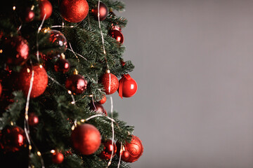 Red balls decorate a Christmas tree on a grey background. Selective focus.