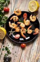 
Shrimp shashlik in a pan, fried in oil and with spices. All this is on the table. Nearby is a plate of shrimp shashals