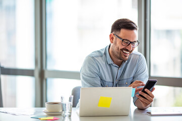 Smiling young man using laptop studying working online at home, happy casual millennial guy typing on pc notebook surfing internet looking at screen enjoying distant job sit at table