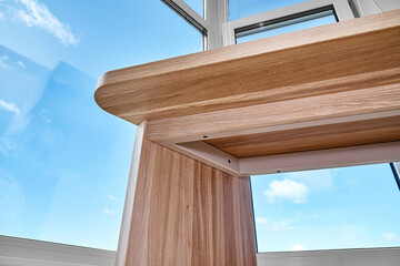 Elegant writing desk made with bleached solid oak timber stands on a cork floor against the sky...