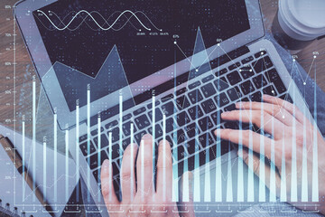 Obraz na płótnie Canvas Double exposure of man's hands typing over computer keyboard and forex graph hologram drawing. Top view. Financial markets concept.