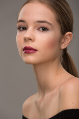 portrait of a beautiful teen girl with exquisite makeup with red lipstick on a gray background