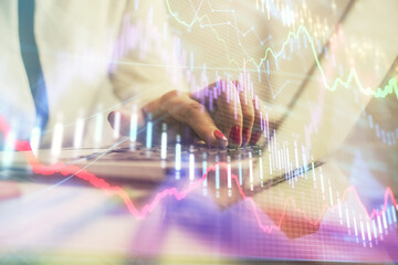 Double exposure of businesswoman hands typing on computer and financial graph hologram drawing. Stock market analysis concept.