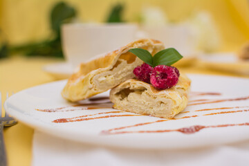 Roll with cottage cheese and raspberries poured with soft caramel on a white ceramic plate.