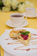 Roll with cottage cheese and raspberries poured with soft caramel on a white ceramic plate.
