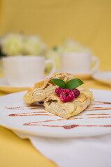 Roll with cottage cheese and raspberries poured with soft caramel on a white ceramic plate.