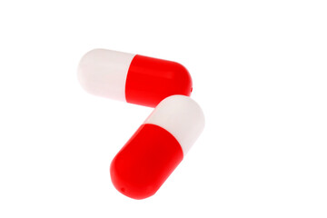 Two red-and-white pills, close-up. On a white background, isolated.