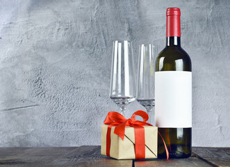 wine glasses, bottle and gift on a wooden table