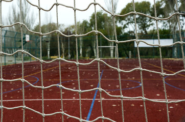 Closeup of white net on the football gate against empty red sports ground