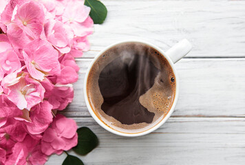 Beautiful hydrangea flowers and coffee cup on rustic white wood, flat lay.