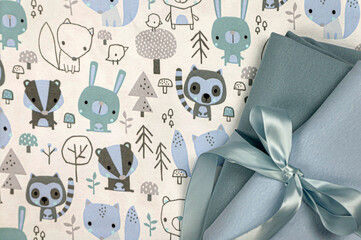 White fabric with a children's pattern on a light background with a satin ribbon