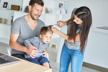 Mutter schneidet die Haare von ihrem Sohn