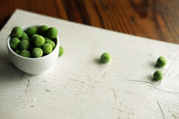 frozen green peas in a bowl on white wooden board
