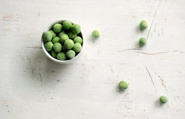 frozen green peas in a bowl on white wooden board