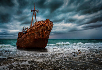 A stranded shipwreck at surf with rough sea and stormy sky