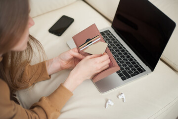 Beautiful girl holding gold credit card in hands and using laptop computer to perform shopping online by inputting card information for payment method. Ecommerce business concept.