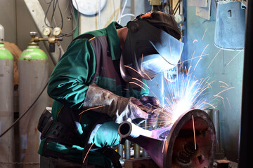 Welder in protective clothing at the workplace in an industrial company in steel construction