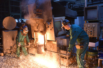 workers in a foundry casting a metal workpiece - safety at work and teamwork