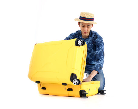 Asian tourists unzipping a bag or to repack suitcase on floor. Stylish man packing suitcase on white background. Journey, Travel concept