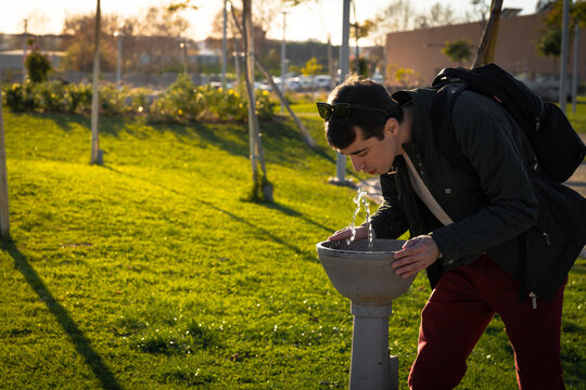 Man drinking water in a fountain in a park